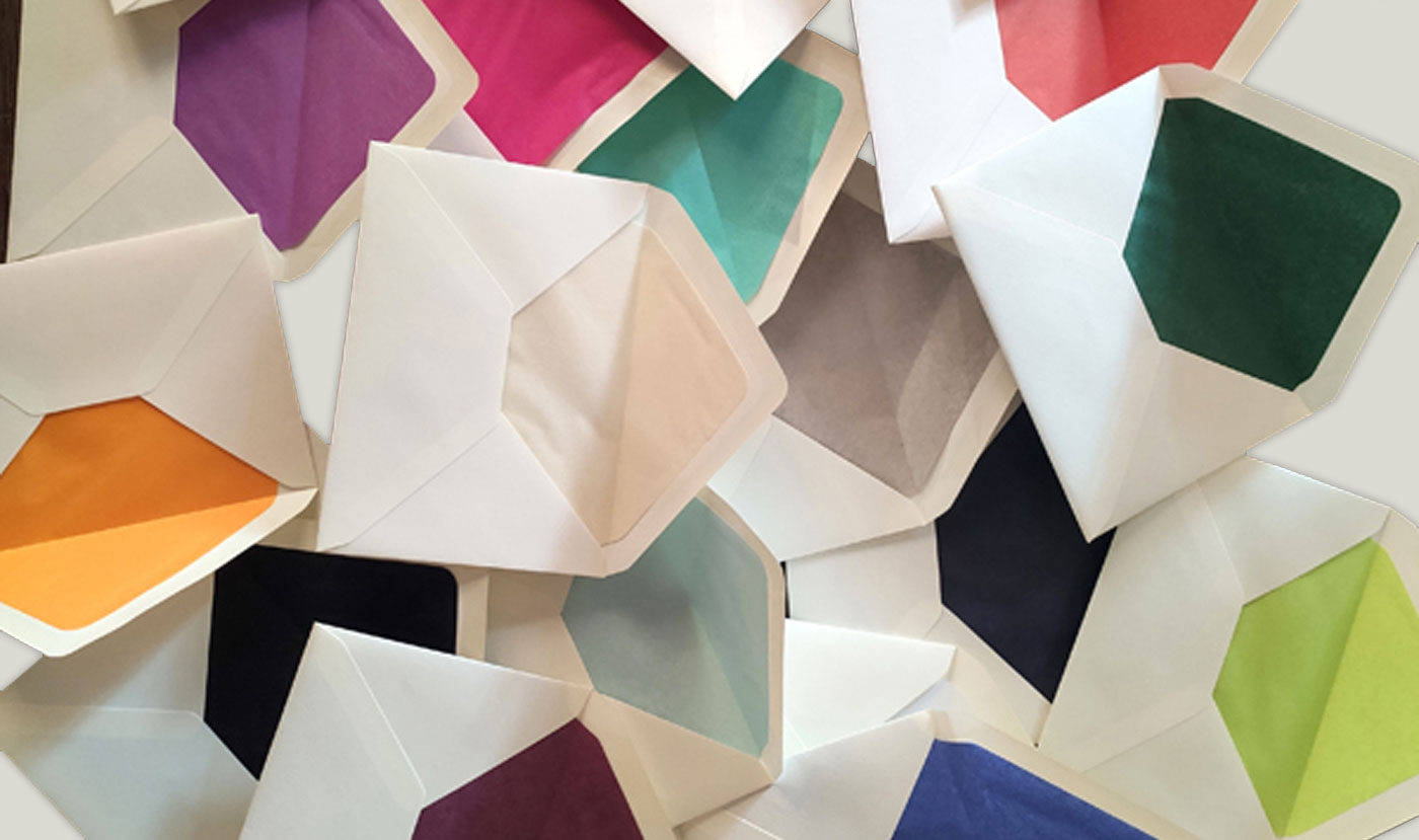 Verschiedene bunte Kuverts mit farbigem Innenfutter, locker auf einem Haufen angeordnet